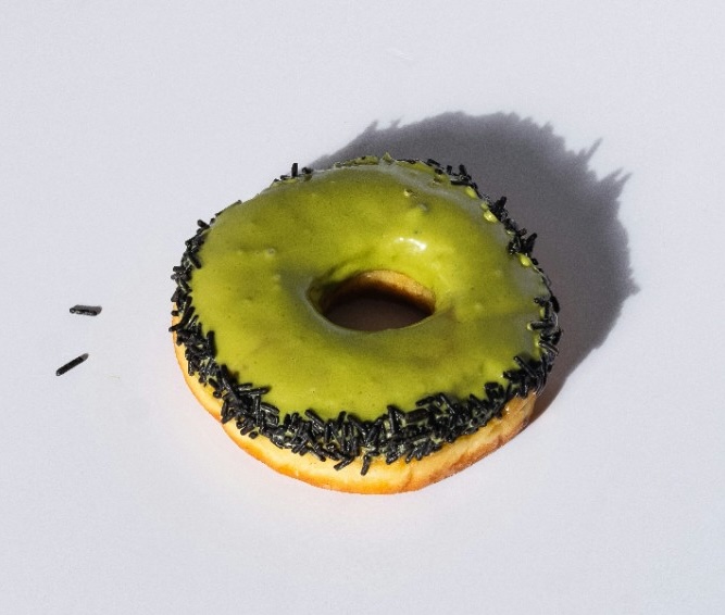 Matcha glazed donut with black sprinkles.