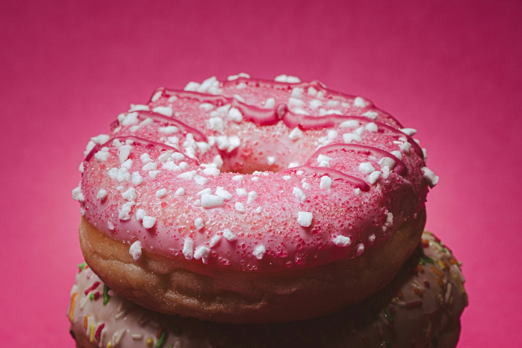 Pink-glazed donuts with pearl sugar on a magenta background